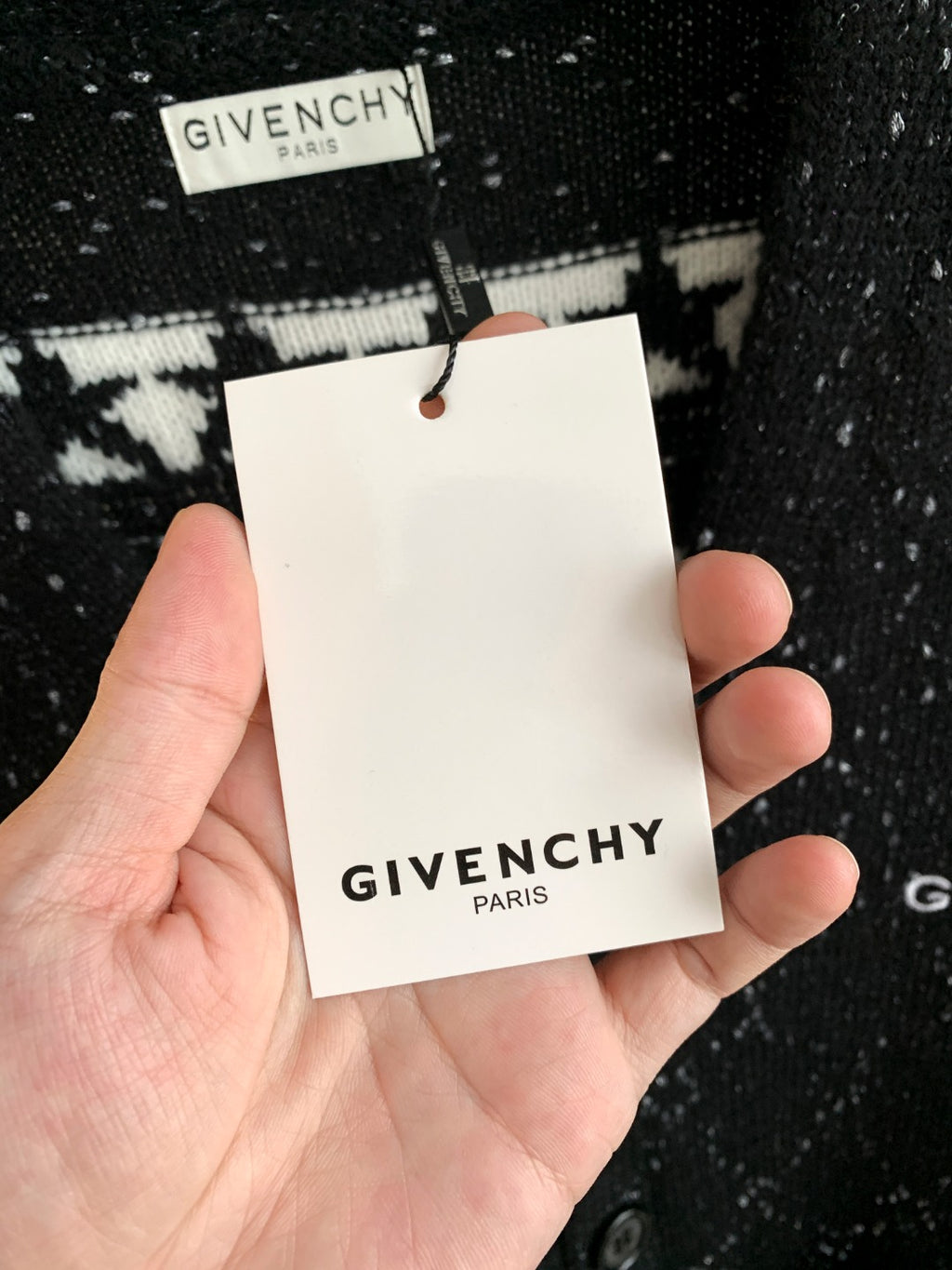 Black speckled cardigan showing white hang tag marked GIVENCHY PARIS.