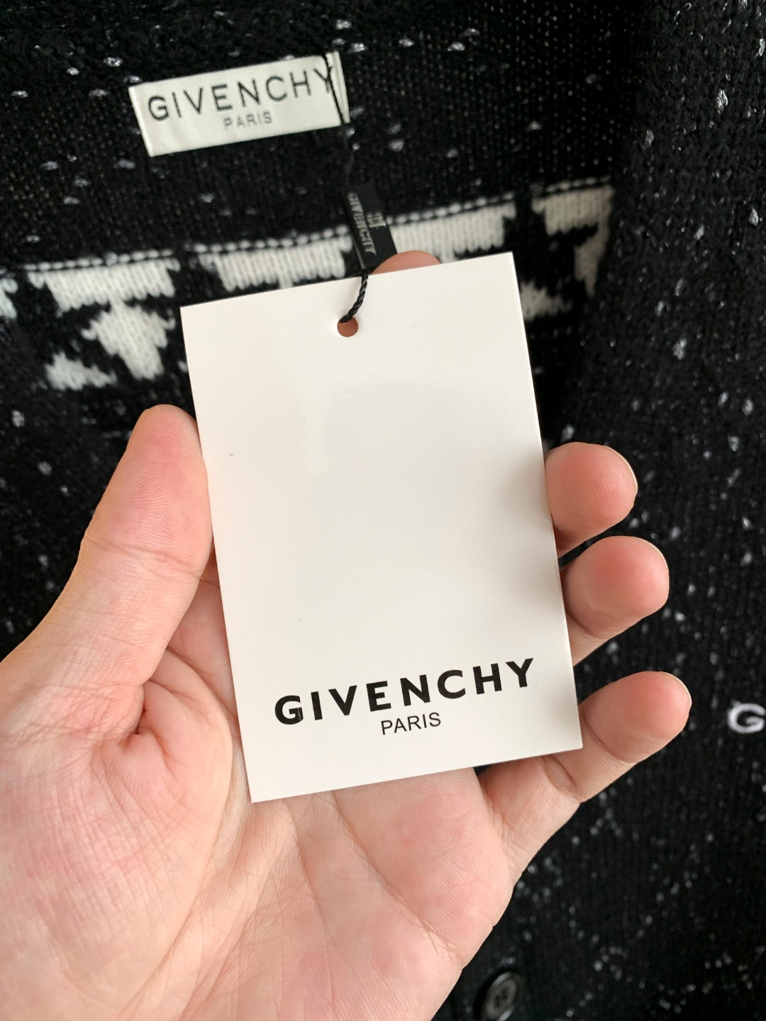 Black speckled cardigan showing white hang tag marked GIVENCHY PARIS.