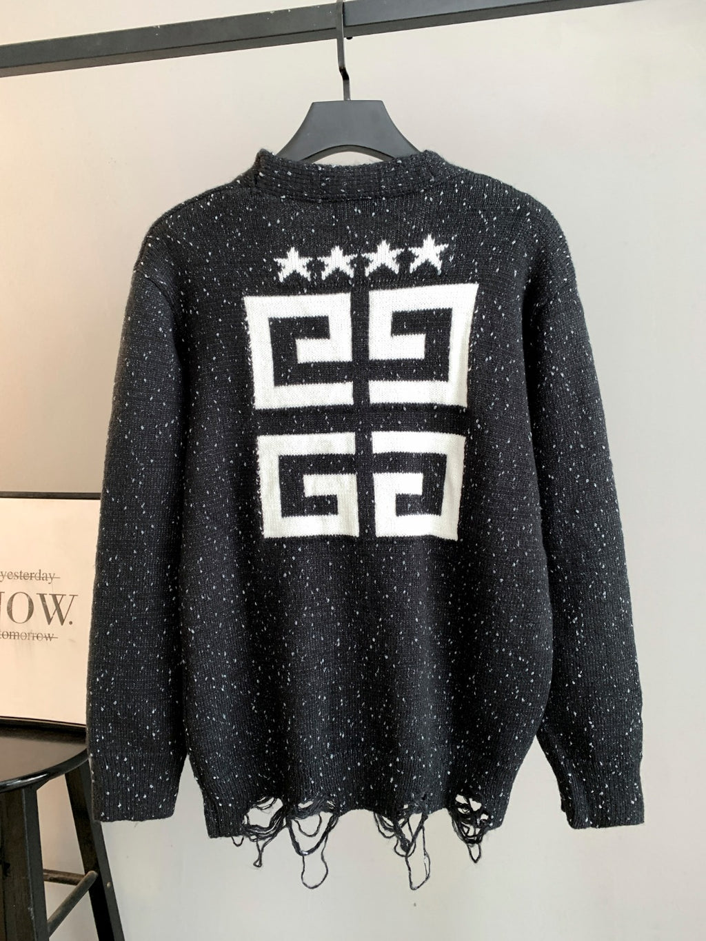 Black cardigan back with large white star and geometric logo print; fringe hem.
