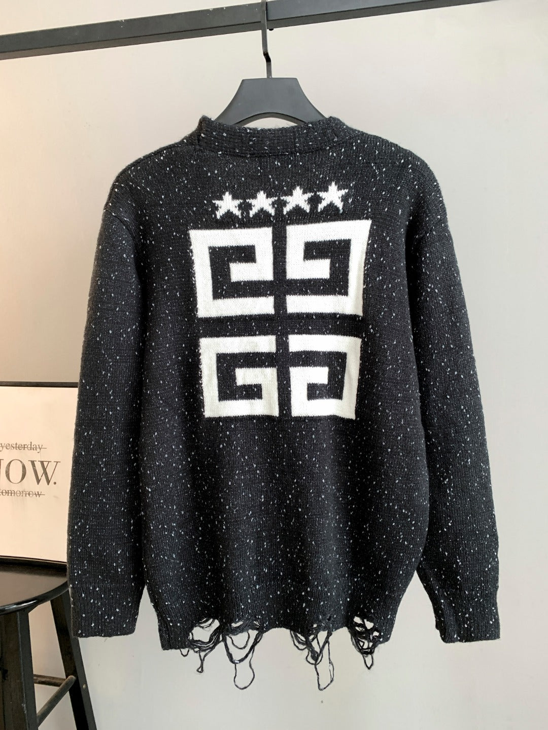 Black cardigan back with large white star and geometric logo print; fringe hem.