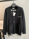 Black speckled cardigan with button front, V-neck, and patterned knit hem fringe.