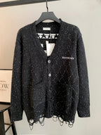 Black speckled cardigan with button front, V-neck, and patterned knit hem fringe.