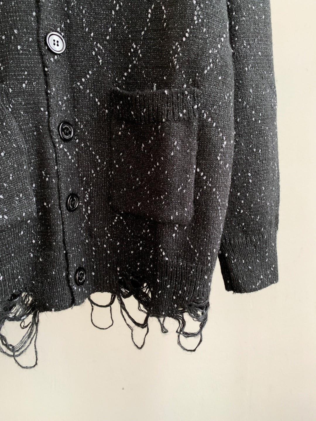 Black cardigan with button front and fringed knit hem.