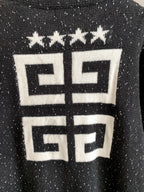 Black cardigan close-up with white geometric logo and star row at upper back.