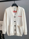 White knit cardigan with V-neck, black button front and two patch pockets