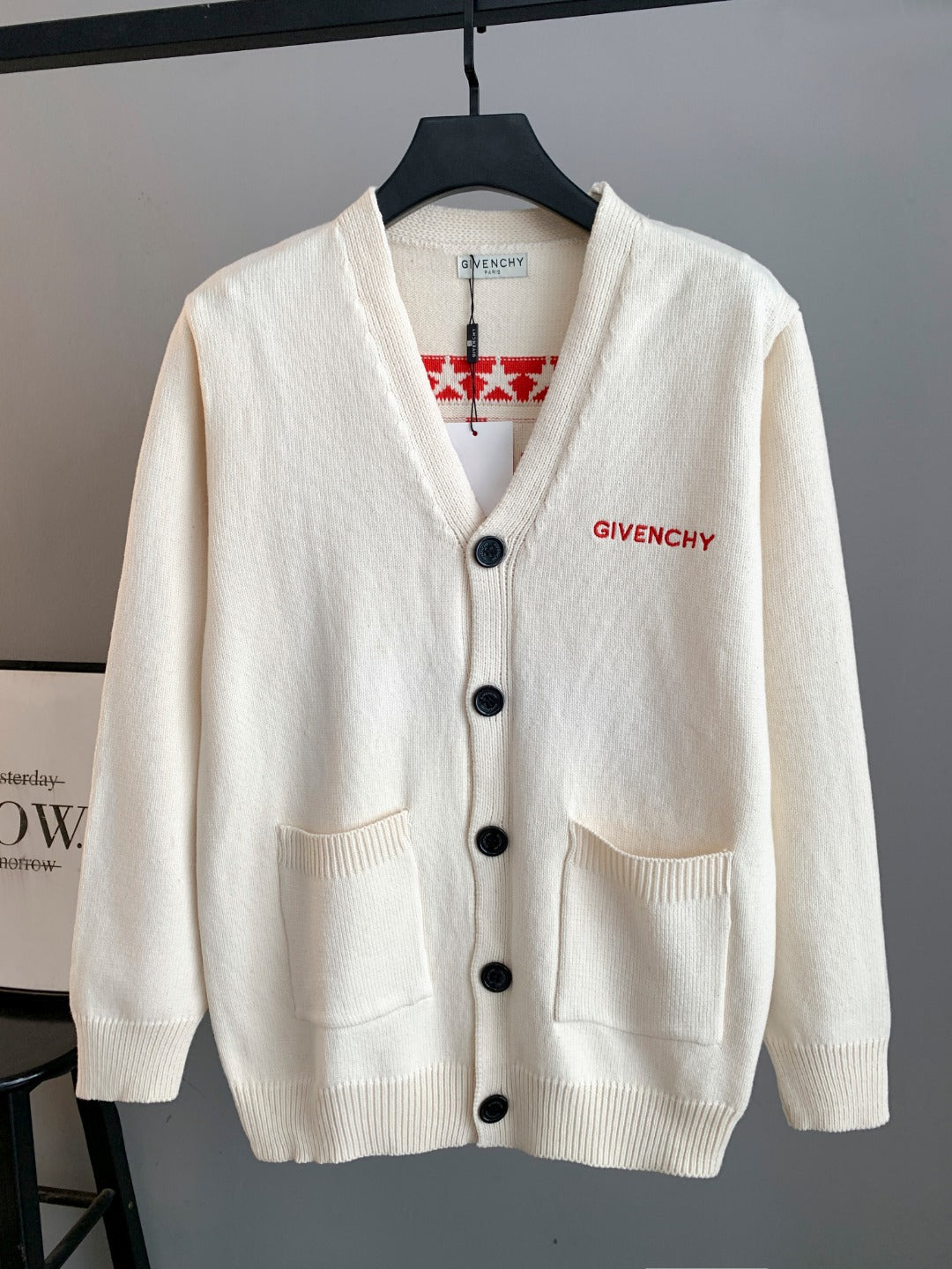 White knit cardigan with V-neck, black button front and two patch pockets
