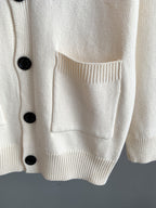 White knit cardigan front pocket with ribbed hem and black button detail