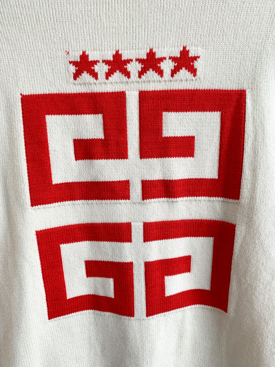 White knit cardigan back close-up of red crest graphic and star motifs