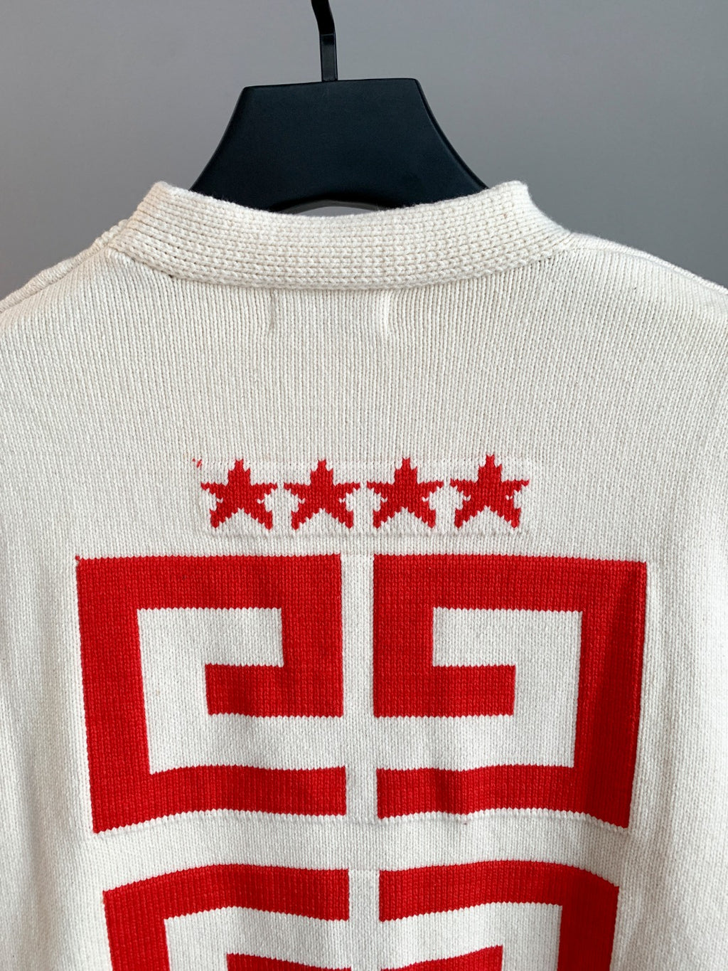 White knit cardigan back close-up with red star row and crest design