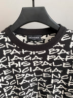 Close-up of black sweater neckline with ribbed crew collar and white repeating logo text