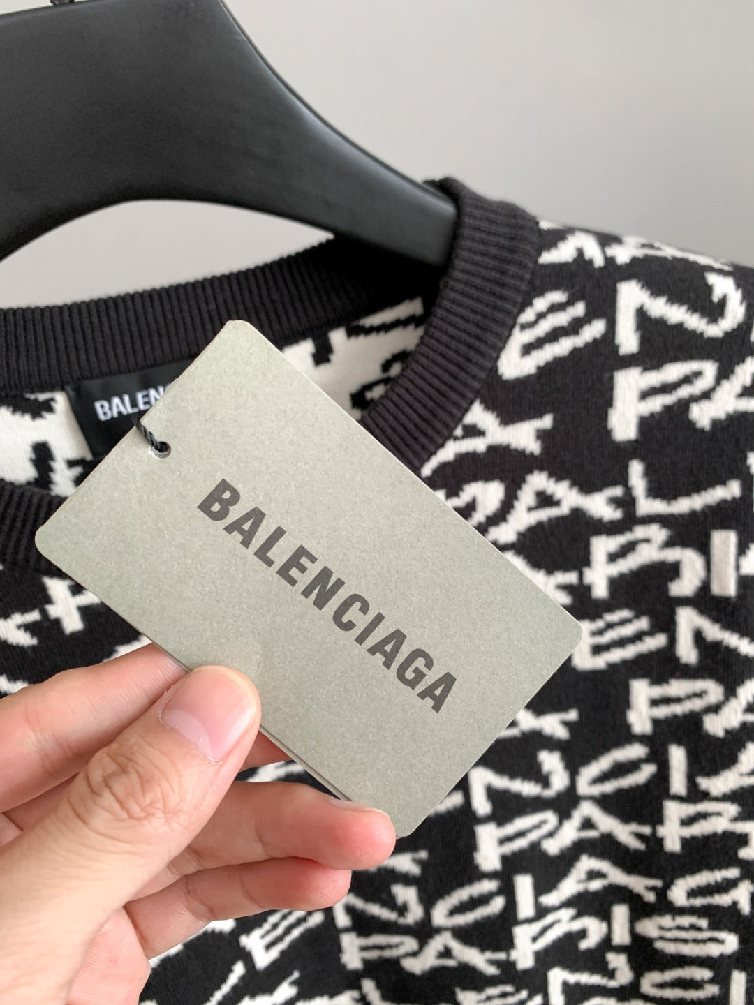 Close-up of black and white logo-knit sweater fabric with brand tag on hanger