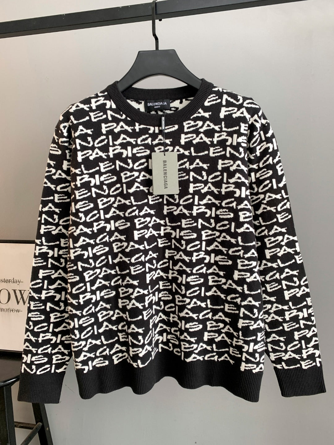 Black long-sleeve sweater with white repeating logo text; ribbed crew neck and cuffs