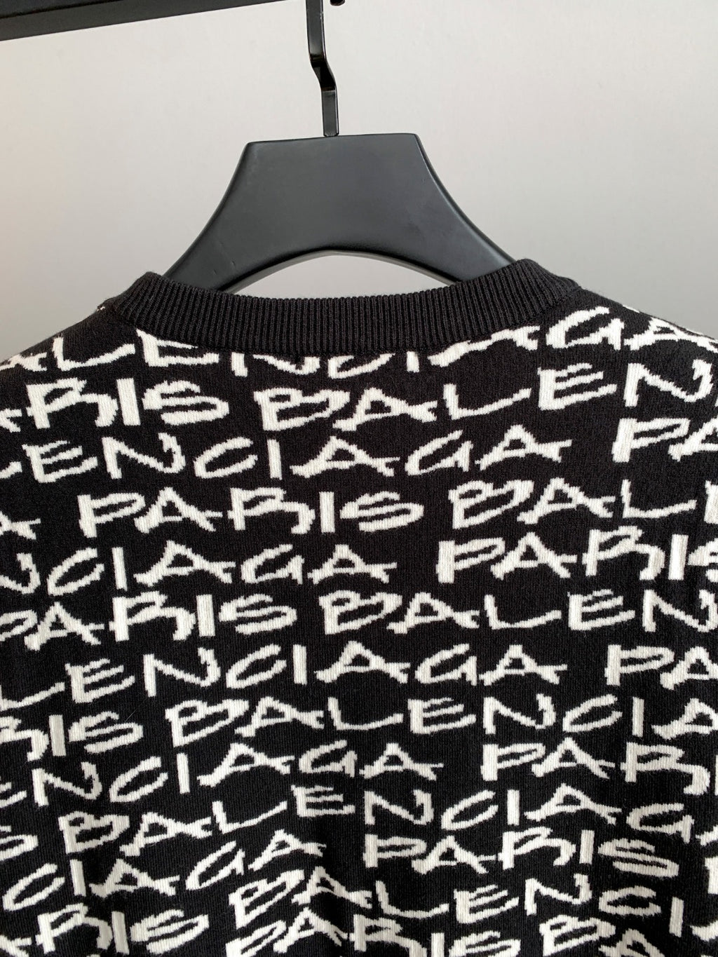 Close-up of black sweater upper body with white repeating logo text