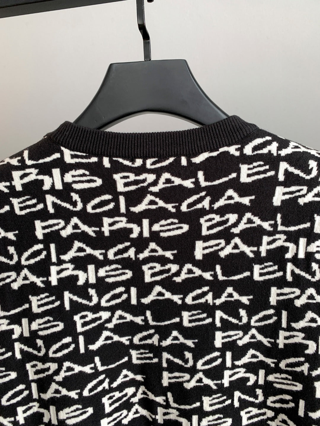 Close-up of black sweater upper body with white repeating logo text