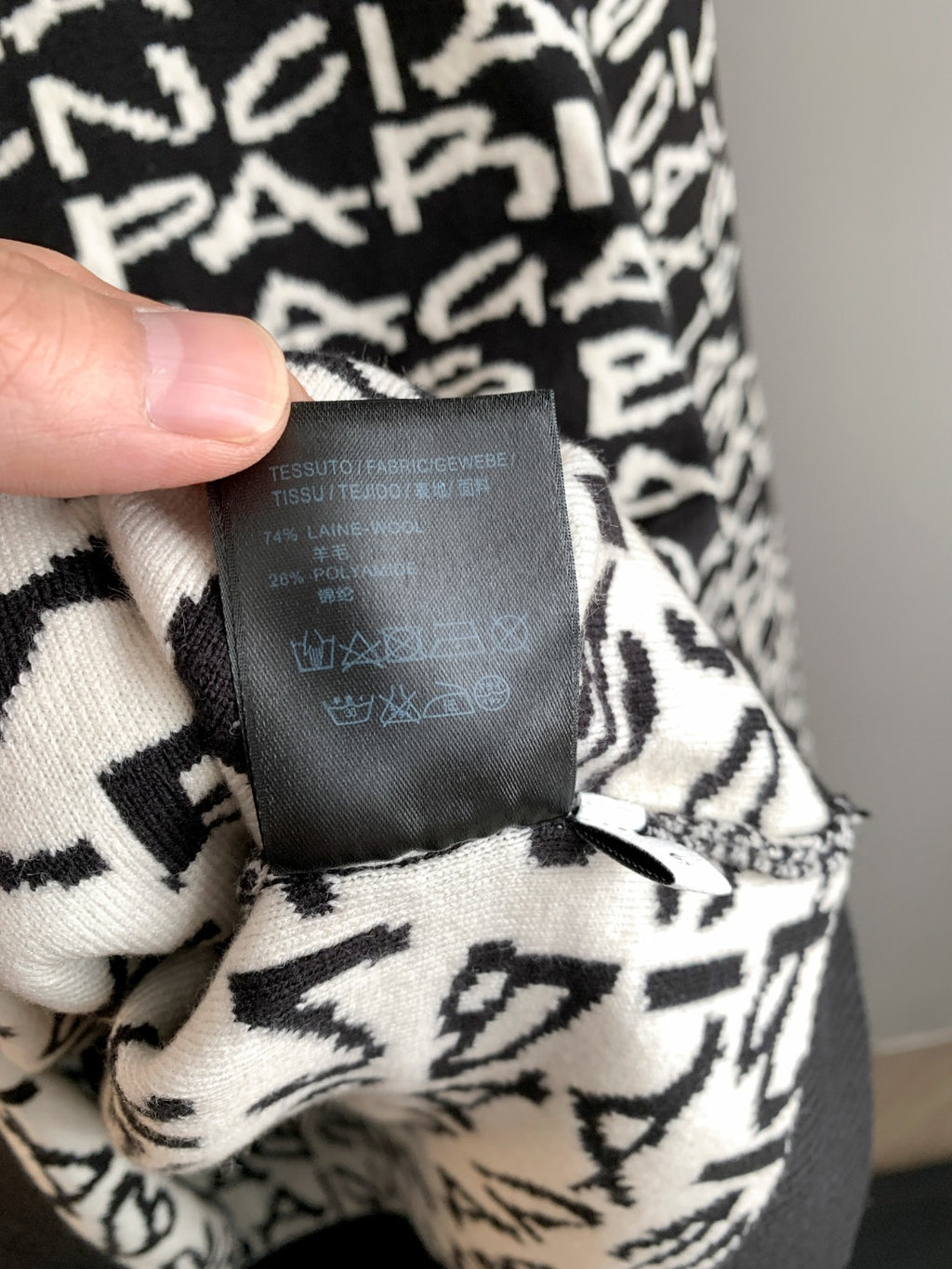 Close-up of sweater care label on black-and-white logo knit fabric