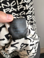 Close-up of sweater care label on black-and-white logo knit fabric