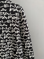 Sleeve side view of black long-sleeve sweater with white repeating logo text