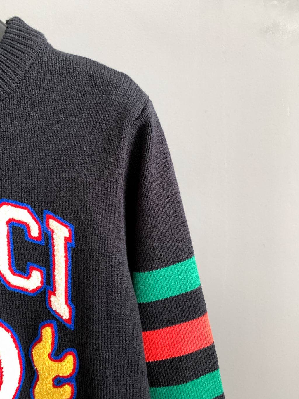 Gucci knit sweater sleeve detail with green and red stripe bands and partial logo