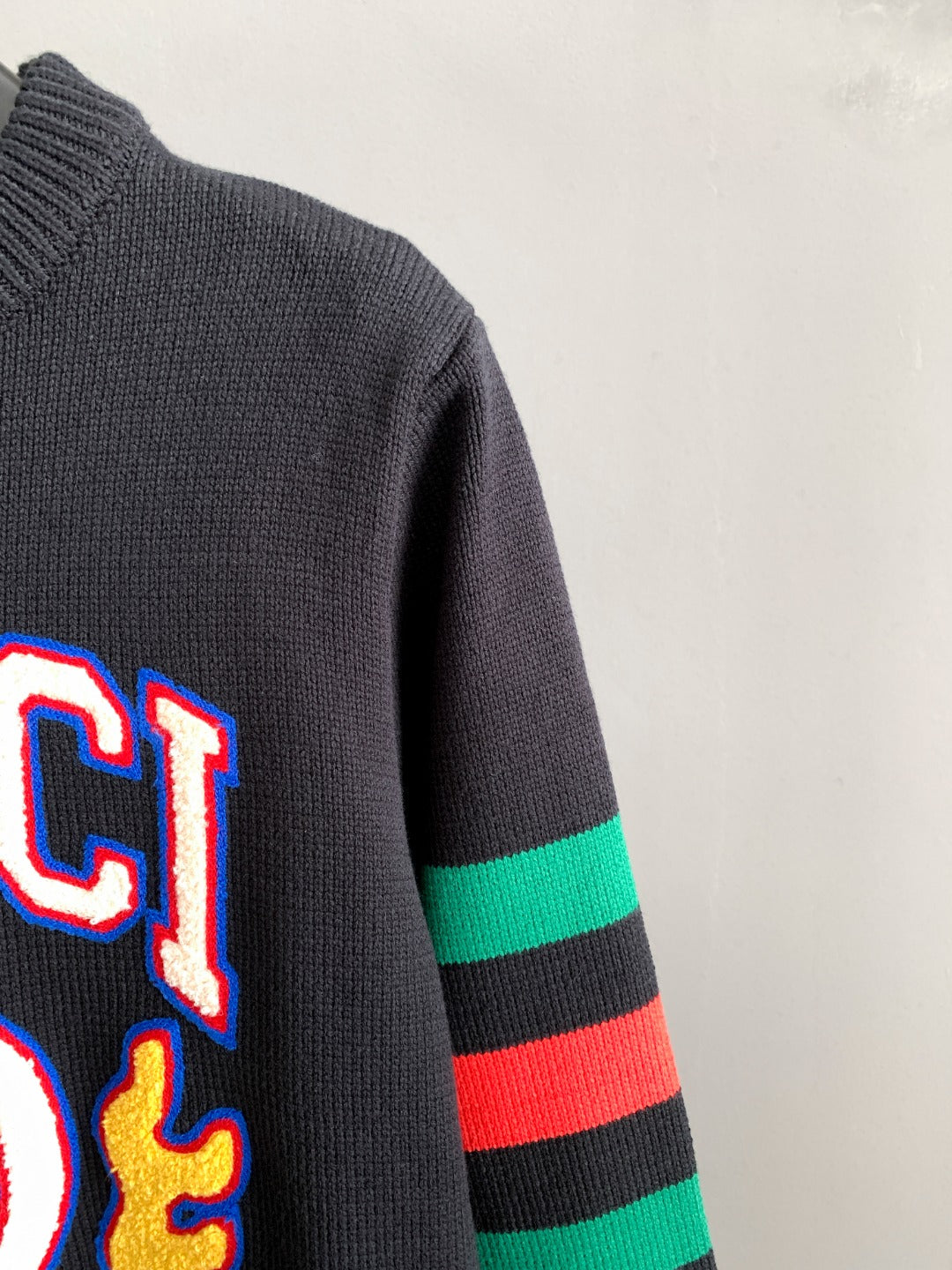 Gucci knit sweater sleeve detail with green and red stripe bands and partial logo