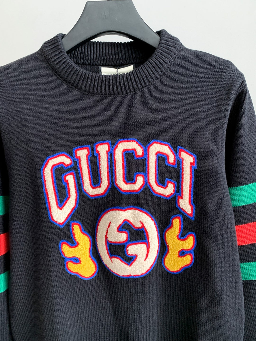 Gucci knit sweater front view in dark gray with colorful “GUCCI” logo