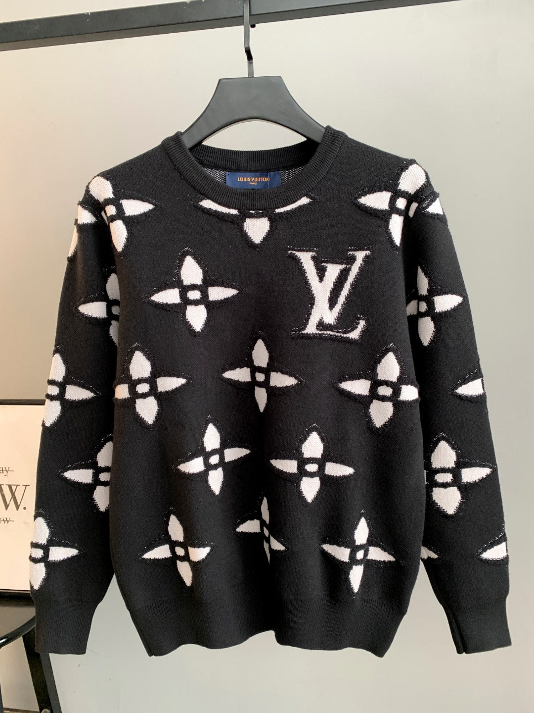 Black knit sweater with white monogram-style geometric pattern, crew neck, long sleeves