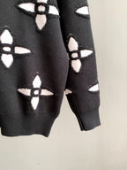 Black knit sweater sleeves with repeating white geometric monogram-style pattern