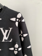 Black knit sweater shoulder and sleeve with white geometric monogram pattern
