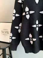 Black knit sweater with white monogram-style pattern, long sleeves