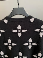 Black knit sweater with white monogram-style pattern and ribbed crew neck