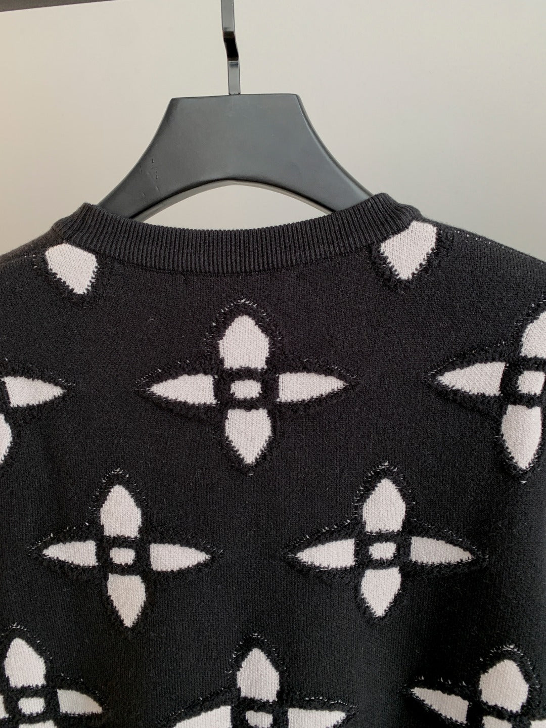 Black knit sweater with white monogram-style pattern and ribbed crew neck