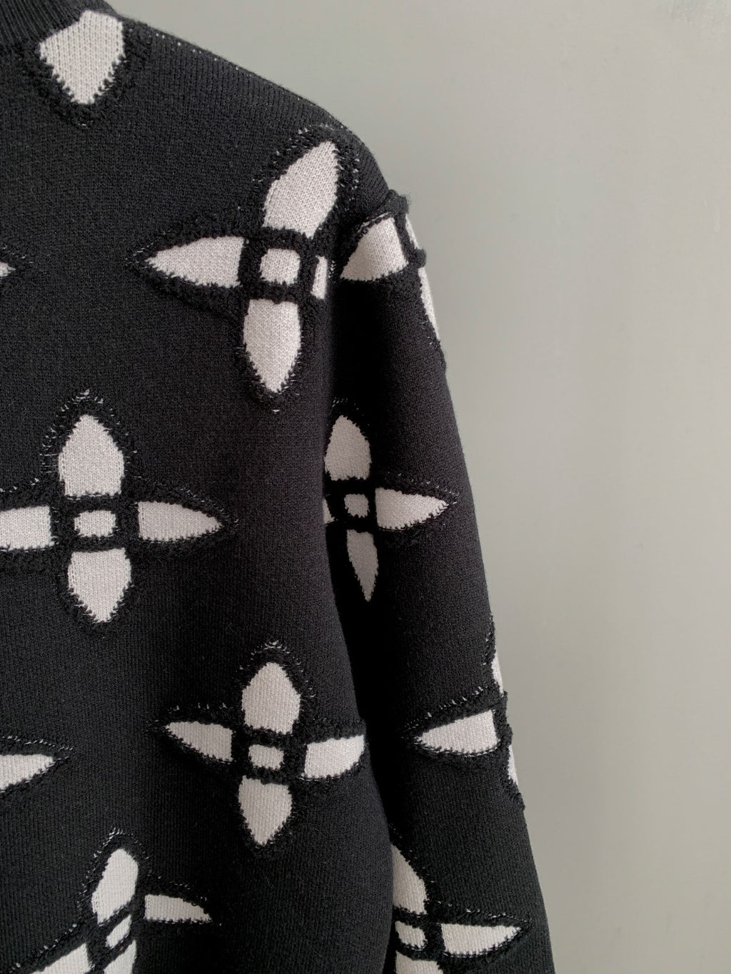 Black knit sweater sleeve with white monogram-style geometric pattern