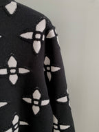 Black knit sweater sleeve with white monogram-style geometric pattern