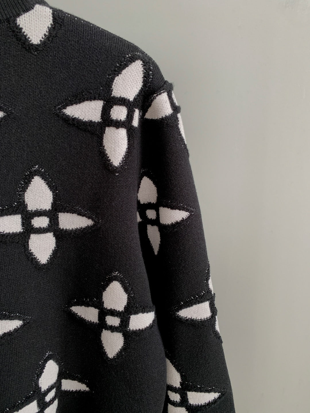 Black knit sweater sleeve with white monogram-style geometric pattern