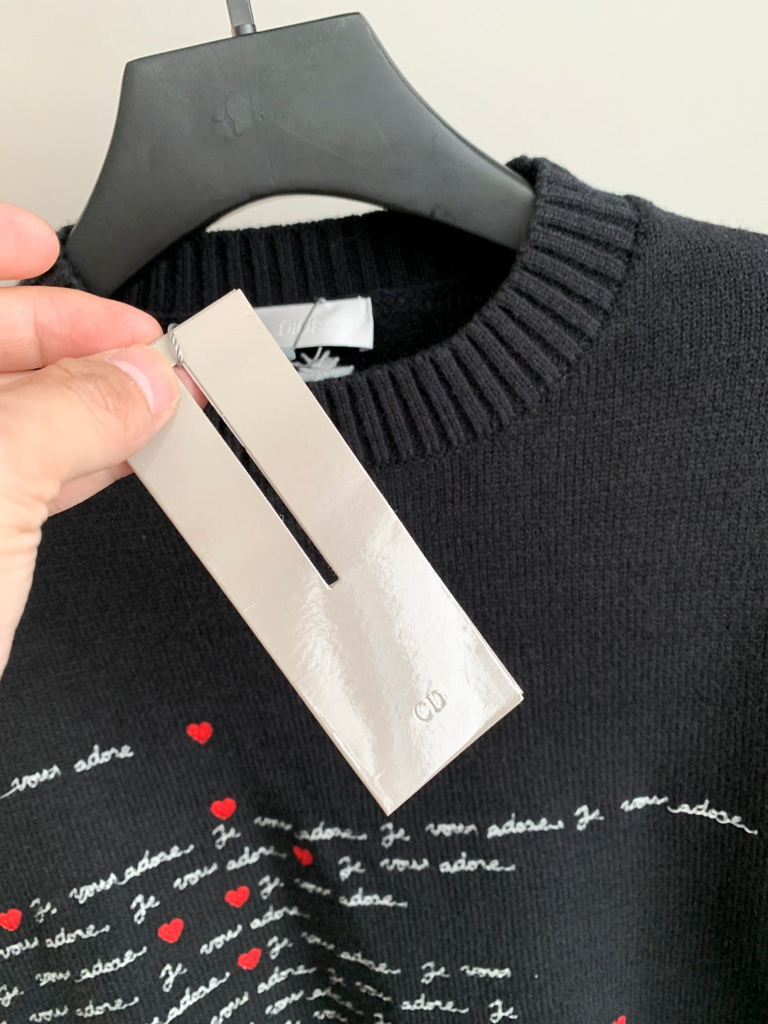 Dark charcoal sweater neckline with hanging size and care labels, part of script graphic