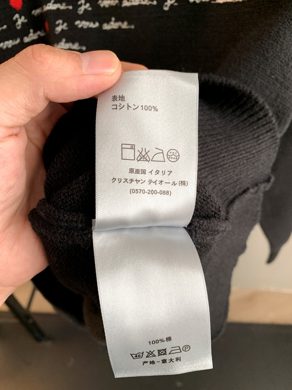 Sweater care label close-up showing 100% fabric icons and washing symbols