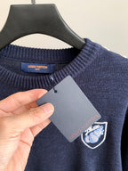 Louis Vuitton crewneck sweater detail with logo crest patch and gray hang tag