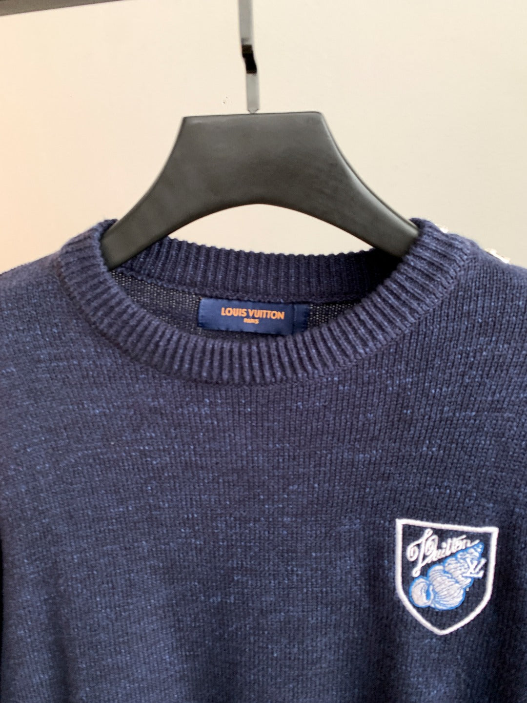 Louis Vuitton crewneck sweater close-up with dark blue knit and crest logo patch