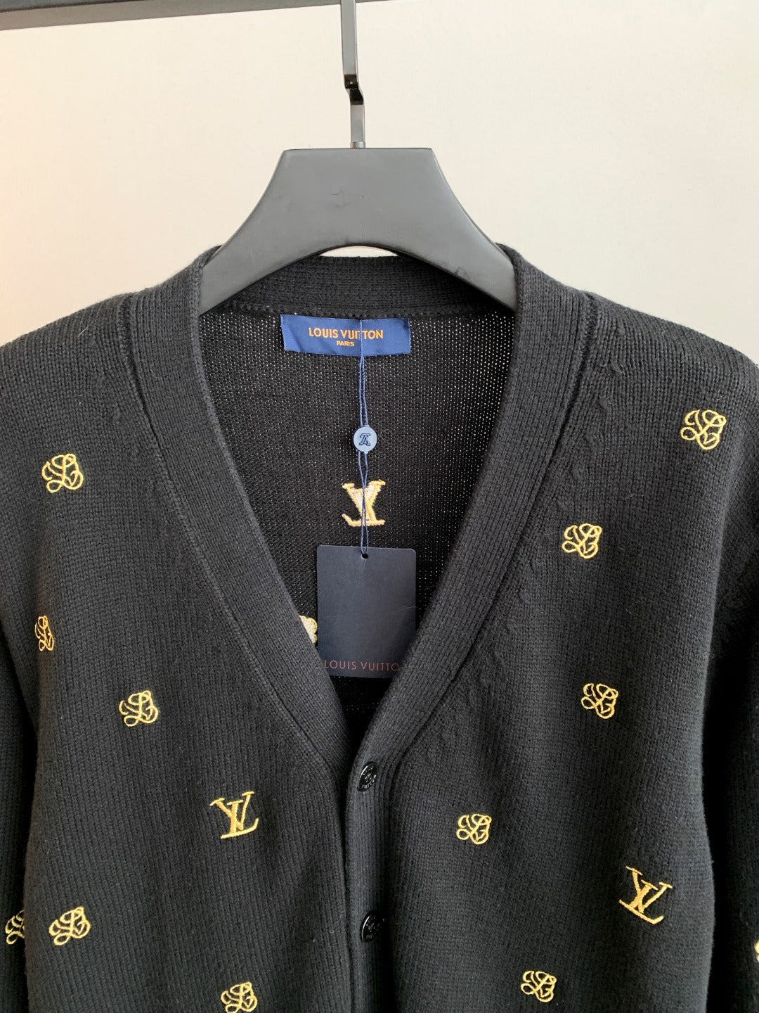 Dark knit cardigan neckline with button placket and gold monogram motifs