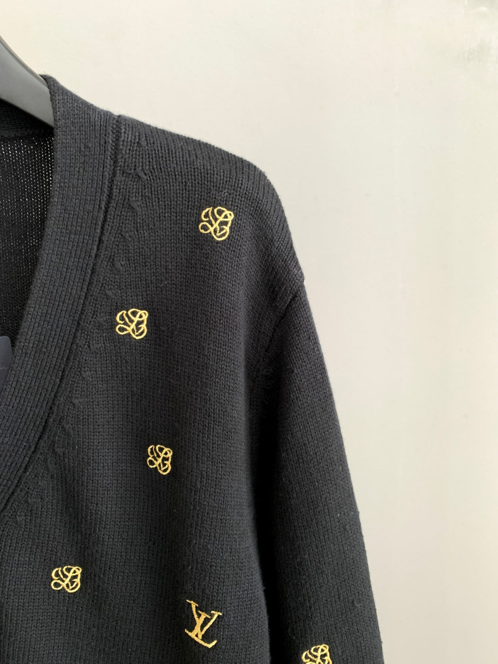 Dark knit cardigan sleeve with small gold monogram accents