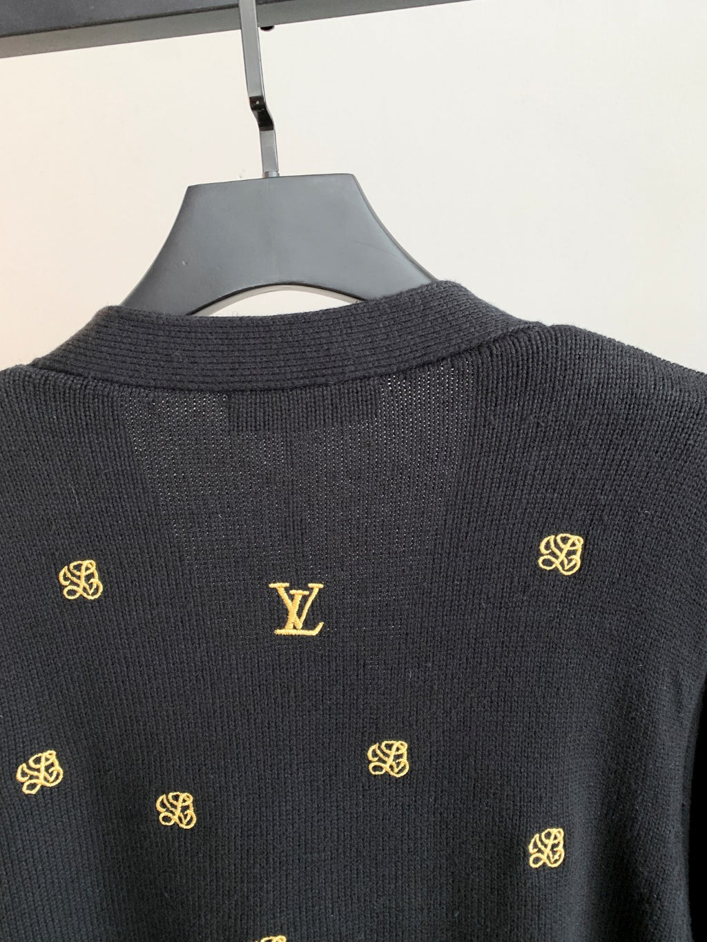 Dark knit cardigan back with gold monogram V-shaped motif and ribbed collar