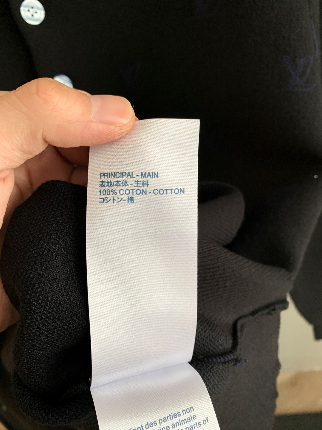 Cotton polo fabric care tag held in hand, text visible on white label