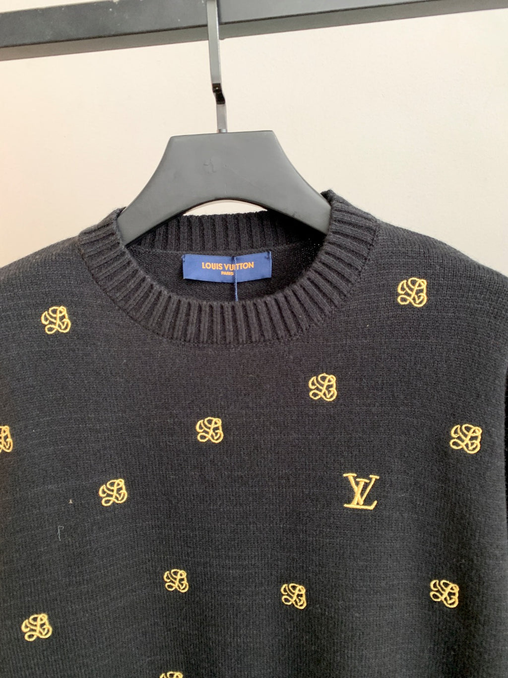 Long-sleeve knit sweater with ribbed crew neck and gold monogram pattern.