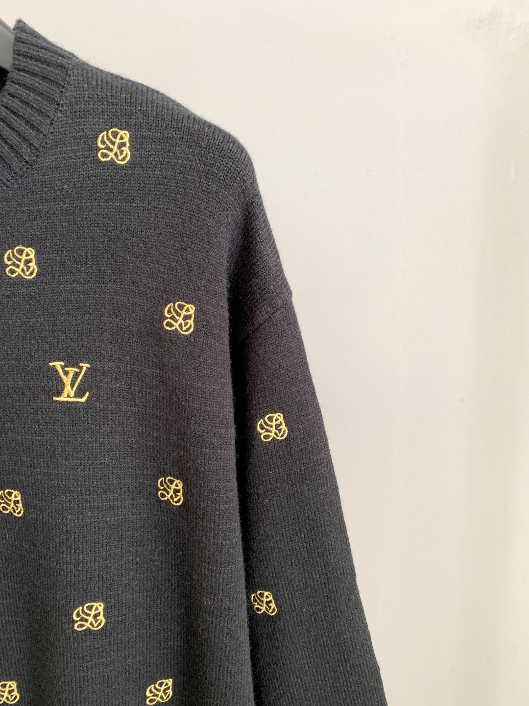 Long-sleeve knit sweater sleeve with gold monogram and LV logo detail.