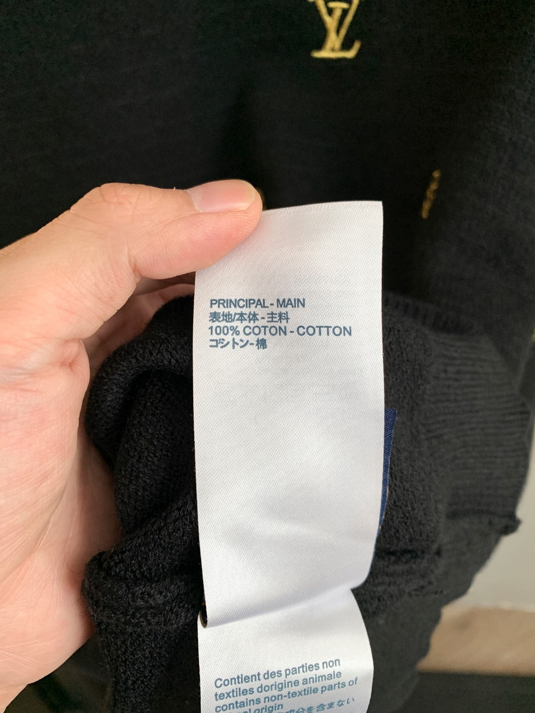 White fabric care label on dark knit sweater: 100% cotton.