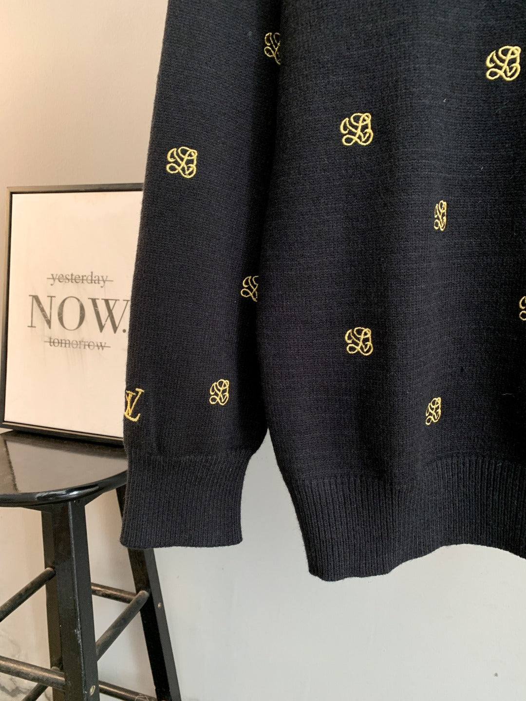 Long-sleeve knit sweater hem with gold monogram print on dark knit.