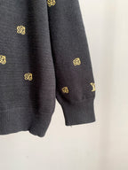 Dark knit sweater sleeve cuff with gold monogram pattern.