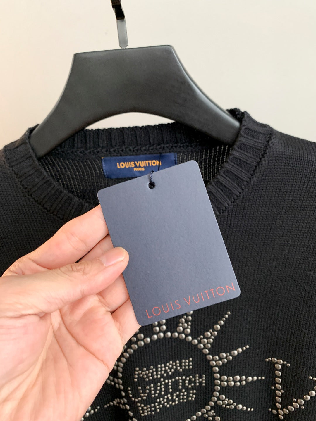 Dark knit sweater collar with inner brand label and paper tag