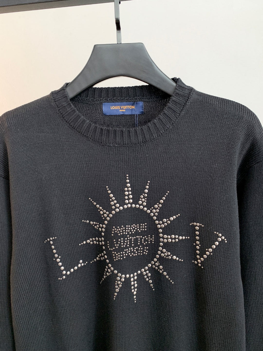 Dark knit long-sleeve sweater with ribbed crew neck and rhinestone emblem