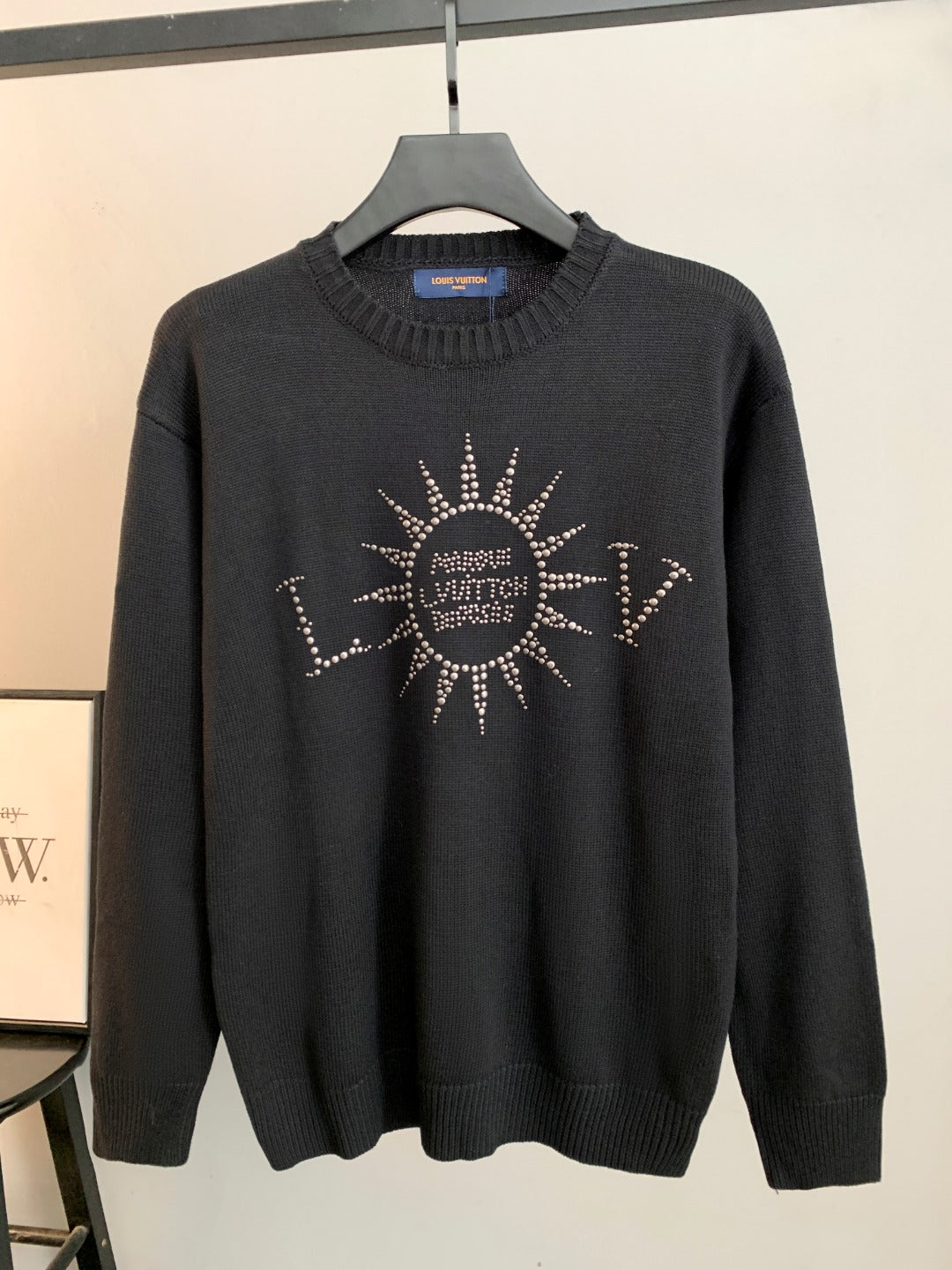 Dark knit long-sleeve sweater with rhinestone emblem on the chest