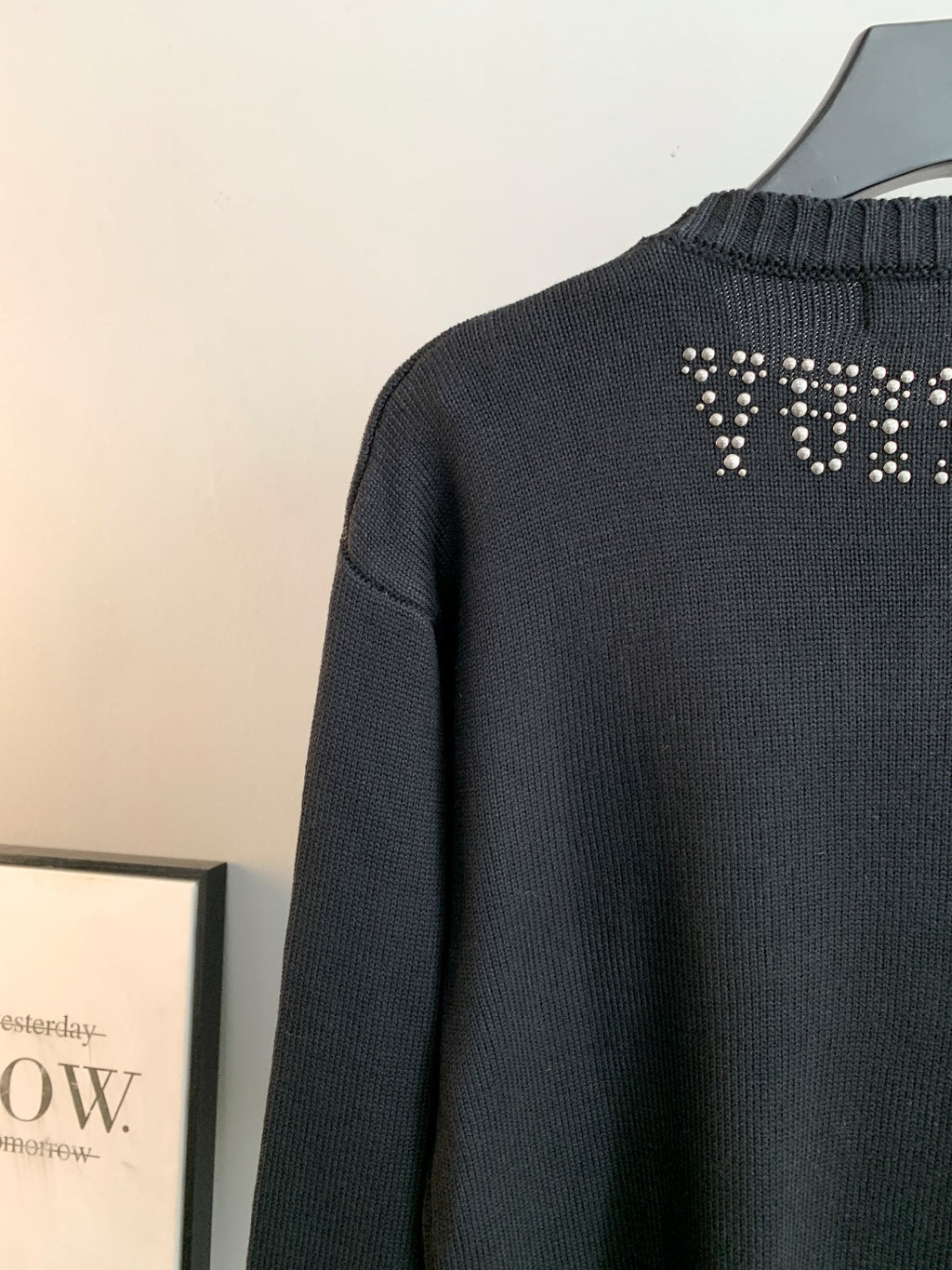 Dark knit sweater back with rhinestone logo near the shoulder